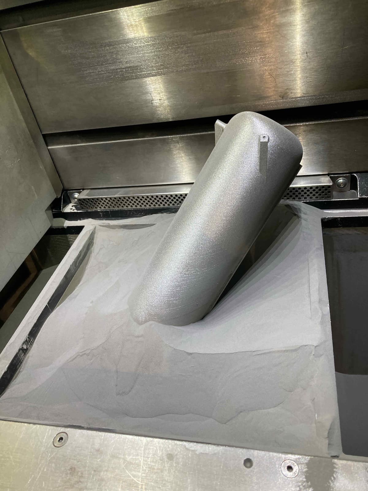A metal LPBF-printed part being revealed in a powder bed at Laser Fusion Solutions